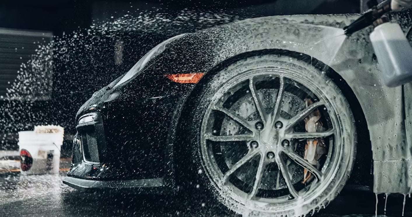 Car wheel being cleaned with foam spray during car wash in Charlotte NC removing dirt and buildup